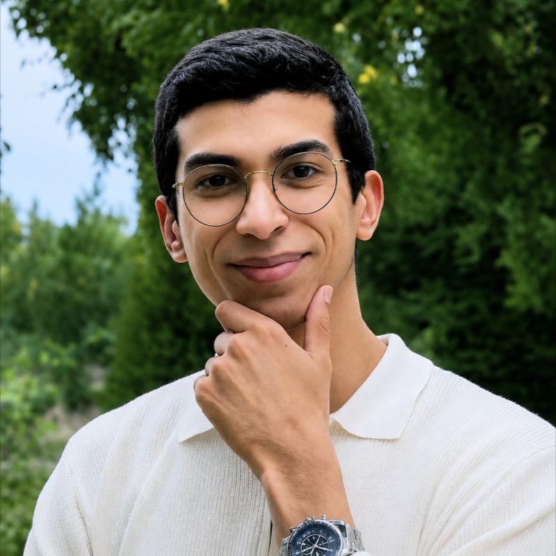 Mohamed Gacha, souriant, la main sous le menton, devant des arbres.